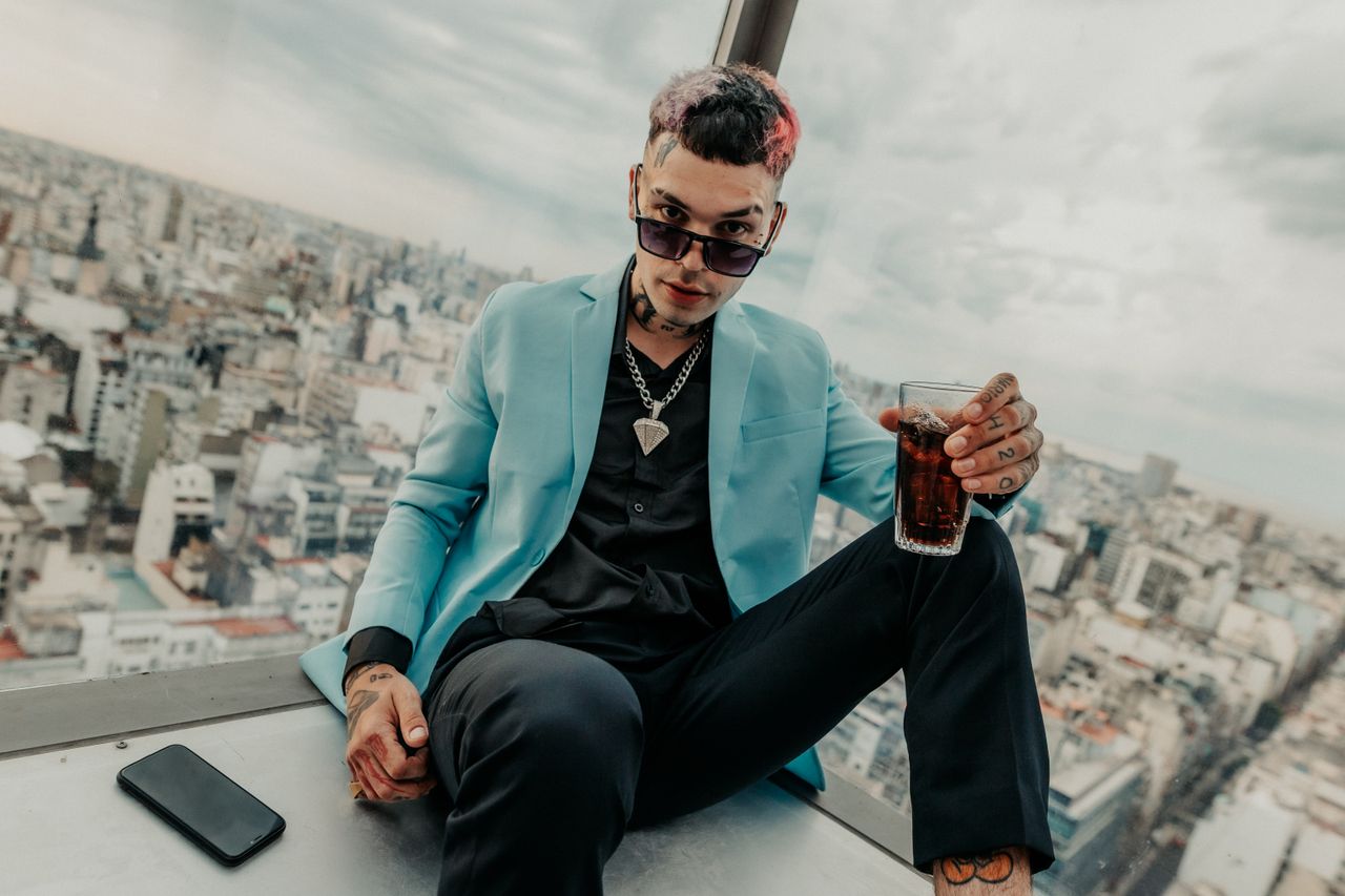 about-img Trendy young man enjoying a drink in a sky lounge with a stunning view of Buenos Aires.
