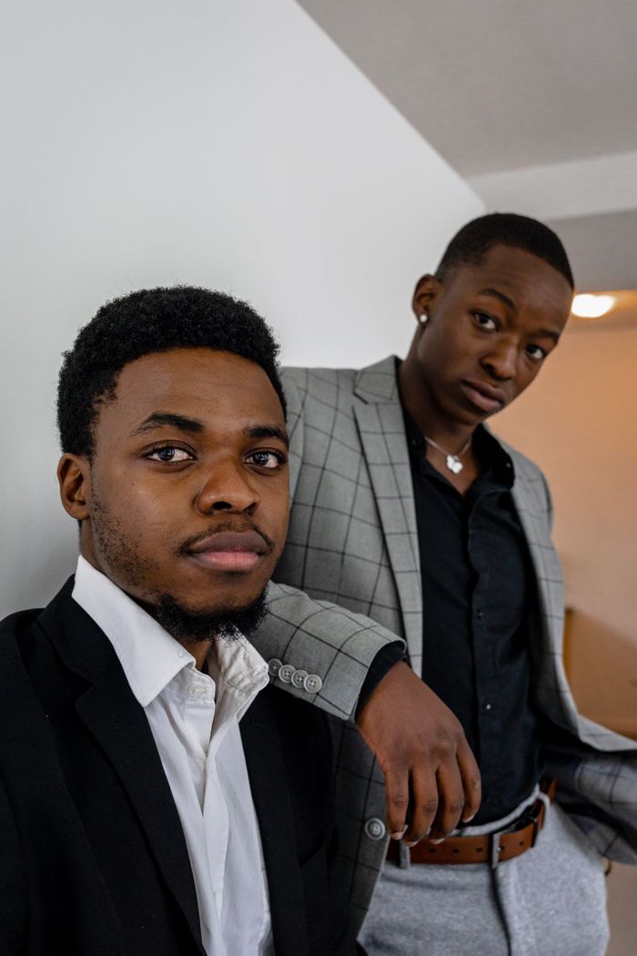 our-experience Two young men in fashionable blazers posing confidently indoors, expressing style and elegance.